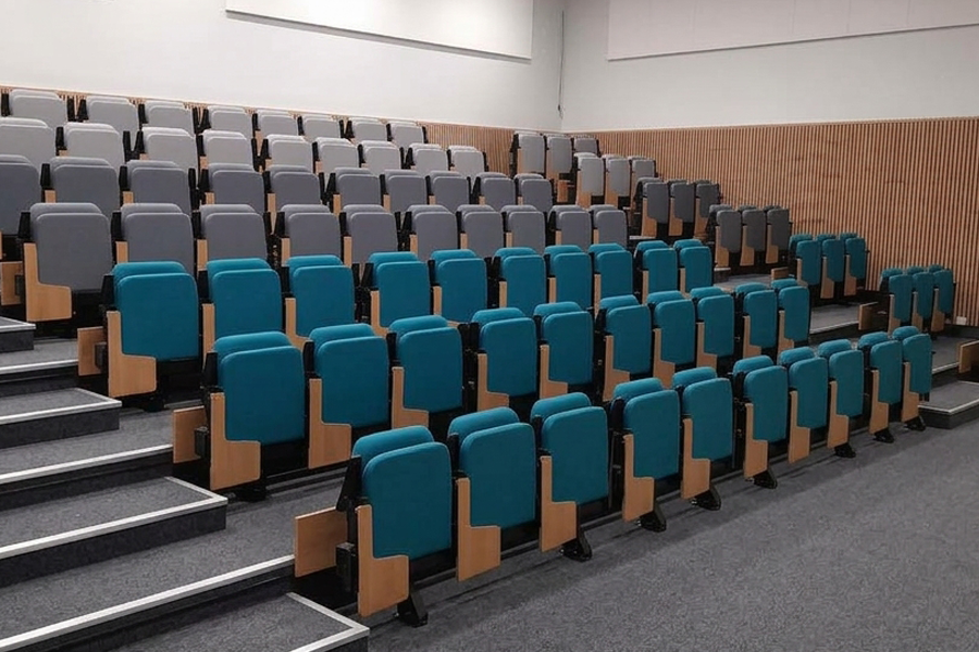 Retractable seating with folding writing tablets. The seats are blue and grey.