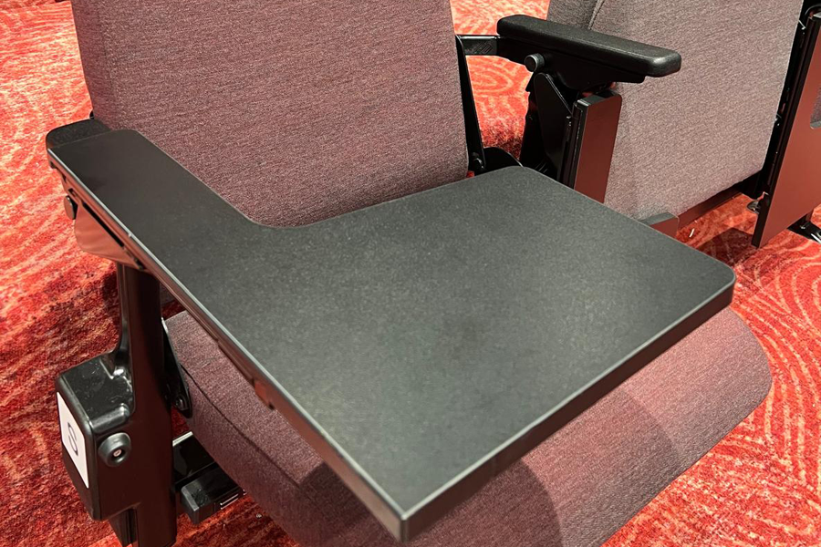 A close up of an open folding seat with a black writing tablet in position and ready to use.
