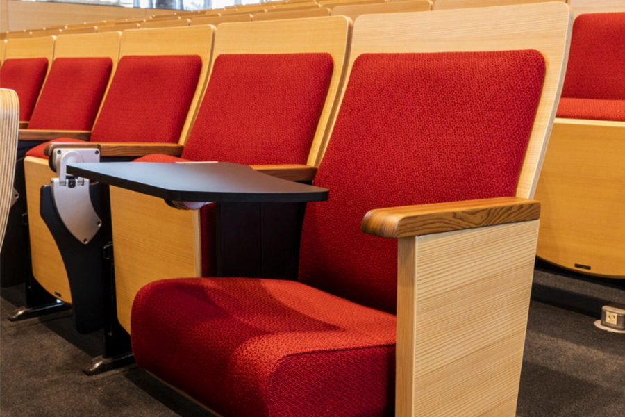 A comfortable auditorium chair with a folding writing tablet.